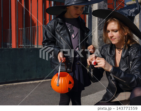 Mother and daughter enjoying Halloween trick or treat in neighborhood Mother and daughter enjoying Halloween trick or treat in neighborhood 143771559