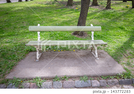 Old wooden park bench in green public garden with grass and trees 143772283