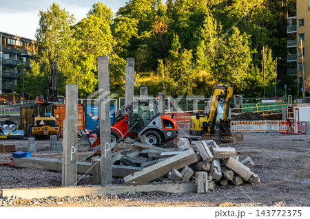 Urban construction site with excavators, concrete debris and foundation work near residential buildings Urban construction site with excavators, concrete debris and foundation work near residential buildings 143772375