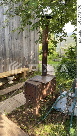 Rusty old wood burning stove with chimney in a rural garden 143772470