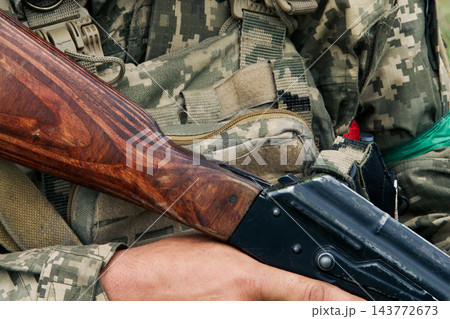 Ukrainian soldier in ghillie helmet holding an assault rifle outdoors 143772673