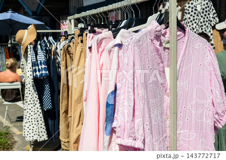 Stylish summer clothing collection on outdoor market rack with pastel linen fashion and casual apparel 143772717