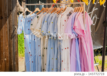 Stylish summer clothing collection on outdoor market rack with pastel linen fashion and casual apparel 143772719