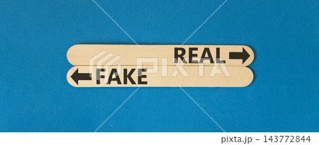 Real or fake words symbol. Concept words Fake and Real on beautiful wooden sticks. Beautiful blue background. Business and real or fake concept. Copy space. Real or fake words symbol. Concept words Fake and Real on beautiful wooden sticks. Beautiful blue background. Business and real or fake concept. Copy space. 143772844