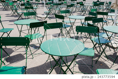 Empty green outdoor cafe tables and chairs in urban public square Empty green outdoor cafe tables and chairs in urban public square 143773594