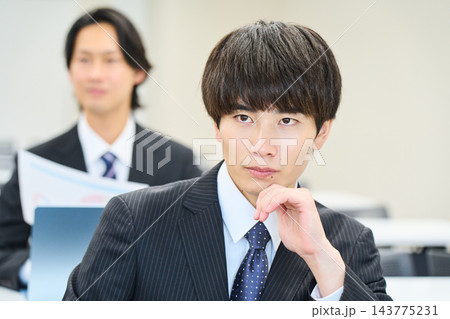オフィスで資料を見ながらチームで仕事をする若い会社員 143775231