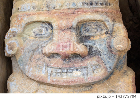 Fanged face of a painted pre-Columbian tomb statue in San Agustin, Colombia 143775704