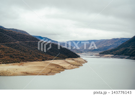Exposed sandy banks with layered patterns beside Zhinvali Reservoir and cloudy mountains, Georgia 143776143