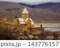 Ananuri church with conical roof and watchtower behind fortress walls and blossoming trees, Georgia 143776157