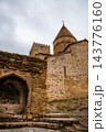 Low angle view of Ananuri fortress stone arch, church dome with golden cross and battlement tower 143776160