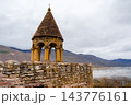 Brick roofed belfry on Ananuri fortress wall overlooking reservoir and misty mountains, Georgia 143776161