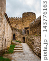 Stone steps and cobbled path through Ananuri fortress courtyard with round tower and arched doors 143776163