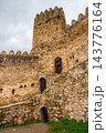 Stone steps and cobbled path through Ananuri fortress courtyard with round tower and arched doors 143776164