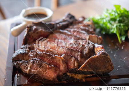 Sliced medium rare Angus prime rib served on a wooden plate. The tender beef with a juicy center, and a beautifully browned crust. Sliced medium rare Angus prime rib served on a wooden plate. The tender beef with a juicy center, and a beautifully browned crust. 143776323