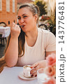 Woman Enjoying Coffee and Dessert at Outdoor Cafe 143776481
