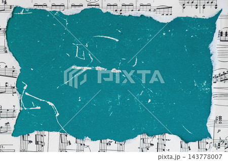 Torn turquoise paper frame on sheet music background mockup. Flat lay mockup of piece of torn turquoise teal paper with copy space placed over a background of vintage sheet music notes 143778007
