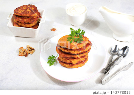 Delicious vegan Russian style pancakes ,blini with pumpkin, pumpkin seeds and parsley, served with a portion of sour cream on a kitchen table, concept for healthy, diet friendly eating. Delicious vegan Russian style pancakes ,blini with pumpkin, pumpkin seeds and parsley, served with a portion of sour cream on a kitchen table, concept for healthy, diet friendly eating. 143778015