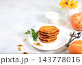 Natural vegan food.Delicious vegan Russian style pancakes ,blini with pumpkin, pumpkin seeds and parsley, served with a portion of sour cream on a kitchen table, concept for healthy, 143778016