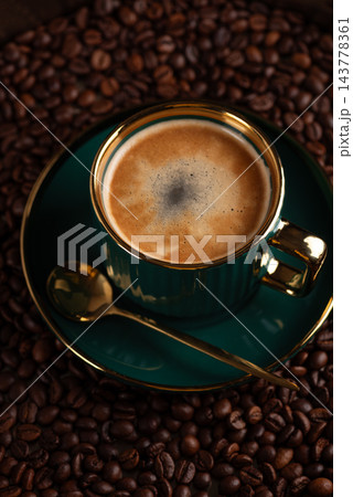 Fresh espresso in green cup with golden spoon on coffee beans Fresh espresso in green cup with golden spoon on coffee beans 143778361