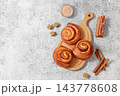 Delicious hot buns rolls on concrete table, accompanied by cinnamon sticks and burnt sugar, traditional autumn and winter dessert for the cold season. Ideal as a design template 143778608