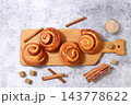 Delicious hot buns rolls on concrete table, accompanied by cinnamon sticks and burnt sugar, traditional autumn and winter dessert for the cold season. Ideal as a design template 143778622