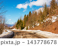 old country road in Carpathian mountains of Ukraine. landscape in late winter. trees on the roadside in morning light. blue sky with fluffy clouds above the distant ridge. travel background old country road in Carpathian mountains of Ukraine. landscape in late winter. trees on the roadside in morning light. blue sky with fluffy clouds above the distant ridge. travel background 143778678
