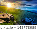 Carpathian mountain on summer solstice landscape. day meet night. sun and moon over meadow with huge stones among the grass on top of the hillside near the peak of mountain range at twilight Carpathian mountain on summer solstice landscape. day meet night. sun and moon over meadow with huge stones among the grass on top of the hillside near the peak of mountain range at twilight 143778689