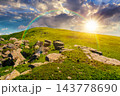 sunset over Carpathian mountain summer landscape. meadow with huge stones among the grass on top of the hillside near the peak of mountain range. dramatic sky with rainbow sunset over Carpathian mountain summer landscape. meadow with huge stones among the grass on top of the hillside near the peak of mountain range. dramatic sky with rainbow 143778690