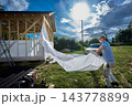 Construction wrap unrolled by builder into long sheet for covering timber frame walls with protective layer against wind and moisture. 143778899