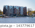 Modern hotel building mercure with steep gabled roofs, moored sailboats, autumn trees, and crisp reflections in calm lake water under clear blue sky in Kaliningrad, Russia 143779617