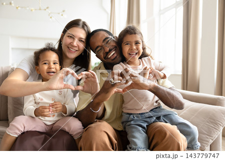 Smiling multiethnic couple with biracial children showing heart gesture Smiling multiethnic couple with biracial children showing heart gesture 143779747