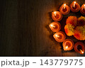 Diwali diyas and marigolds glowing on dark wood 143779775