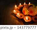 Diwali oil lamps glowing beside orange marigolds on a wooden surface 143779777