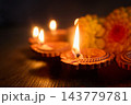 Diwali diya lamps glowing beside marigold flowers 143779781