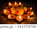 Diwali diyas glowing around a festive flower arrangement 143779796