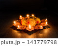 Diwali diyas glowing around festive flowers on a dark wooden floor 143779798