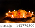 Diwali diyas glowing beside marigold flowers in a dark setting 143779800