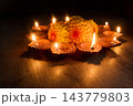 Diwali diya lamps glowing around flowers on a wooden surface 143779803