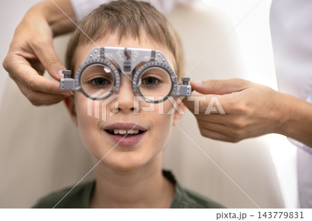 Portrait of child boy wearing trial frame during eye examination Portrait of child boy wearing trial frame during eye examination 143779831