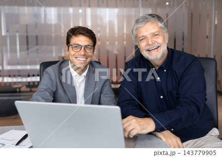 Latino businessmen sitting behind laptop during collaborative meeting Latino businessmen sitting behind laptop during collaborative meeting 143779905