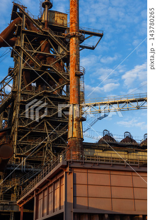 Vertical photo of historic blast furnace steel framework with bright orange conical exhaust stack connecting bridge truss and multi level stairs in Duisburg Ruhr region Westphalia Germany Vertical photo of historic blast furnace steel framework with bright orange conical exhaust stack connecting bridge truss and multi level stairs in Duisburg Ruhr region Westphalia Germany 143780265