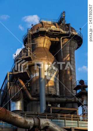 Vertical photo of historic blast furnace cowper stove dome top upper catwalk balconies exhaust piping steel framework and blue sky in Duisburg Ruhr region North Rhine Westphalia Germany Vertical photo of historic blast furnace cowper stove dome top upper catwalk balconies exhaust piping steel framework and blue sky in Duisburg Ruhr region North Rhine Westphalia Germany 143780267