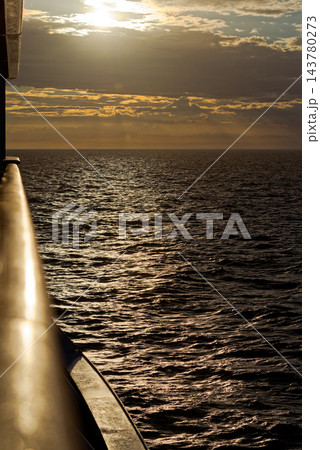 Golden sunset over shimmering sea from ship rail 143780273