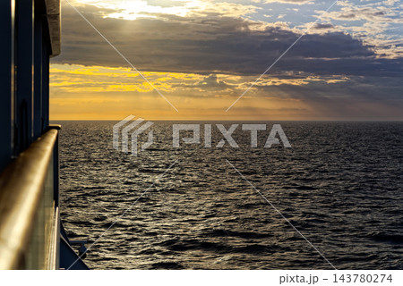 Golden sunset over shimmering open sea from ship rail 143780274