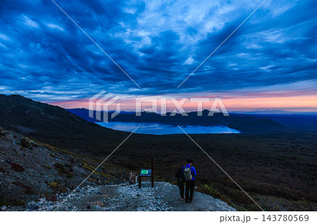 朝焼けに染まる空と支笏湖の絶景を望む樽前山登山道の登山者たち 143780569