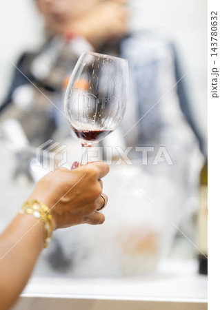 Hand holding a red wine glass at an elegant tasting event Hand holding a red wine glass at an elegant tasting event 143780632