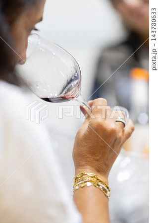 Woman smelling red wine in a glass during a wine tasting Woman smelling red wine in a glass during a wine tasting 143780633