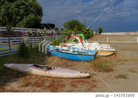 Old pedal boats, rowing boat and kayak on empty beach at end of season, Calabria, Italy 143781000