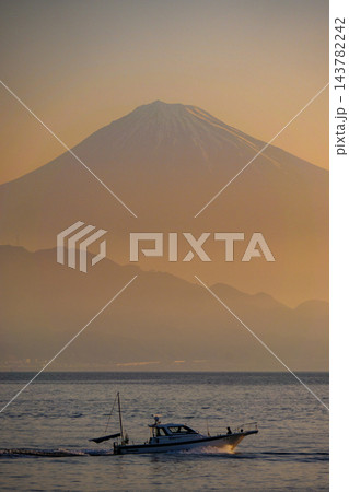 【静岡県】朝のオレンジ色に染まる富士山と海を行く釣り船 縦位置 143782242
