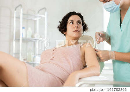 Male anesthesiologist injecting medicine with syringe into the shoulder of female patient Male anesthesiologist injecting medicine with syringe into the shoulder of female patient 143782863